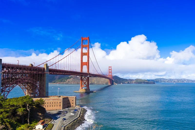 The Golden Gate Bridge spans blue water under a bright sky.