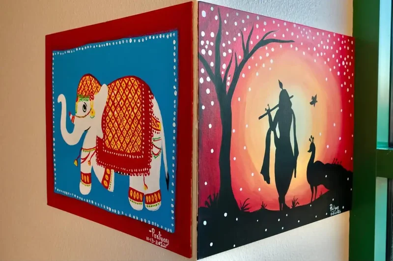 A decorative cube with painted elephants and silhouettes on its colorful sides.