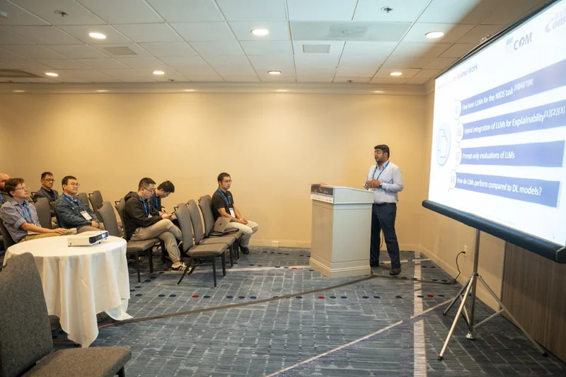 Presenting research on language models for intrusion detection to an audience at MILCOM 2025.